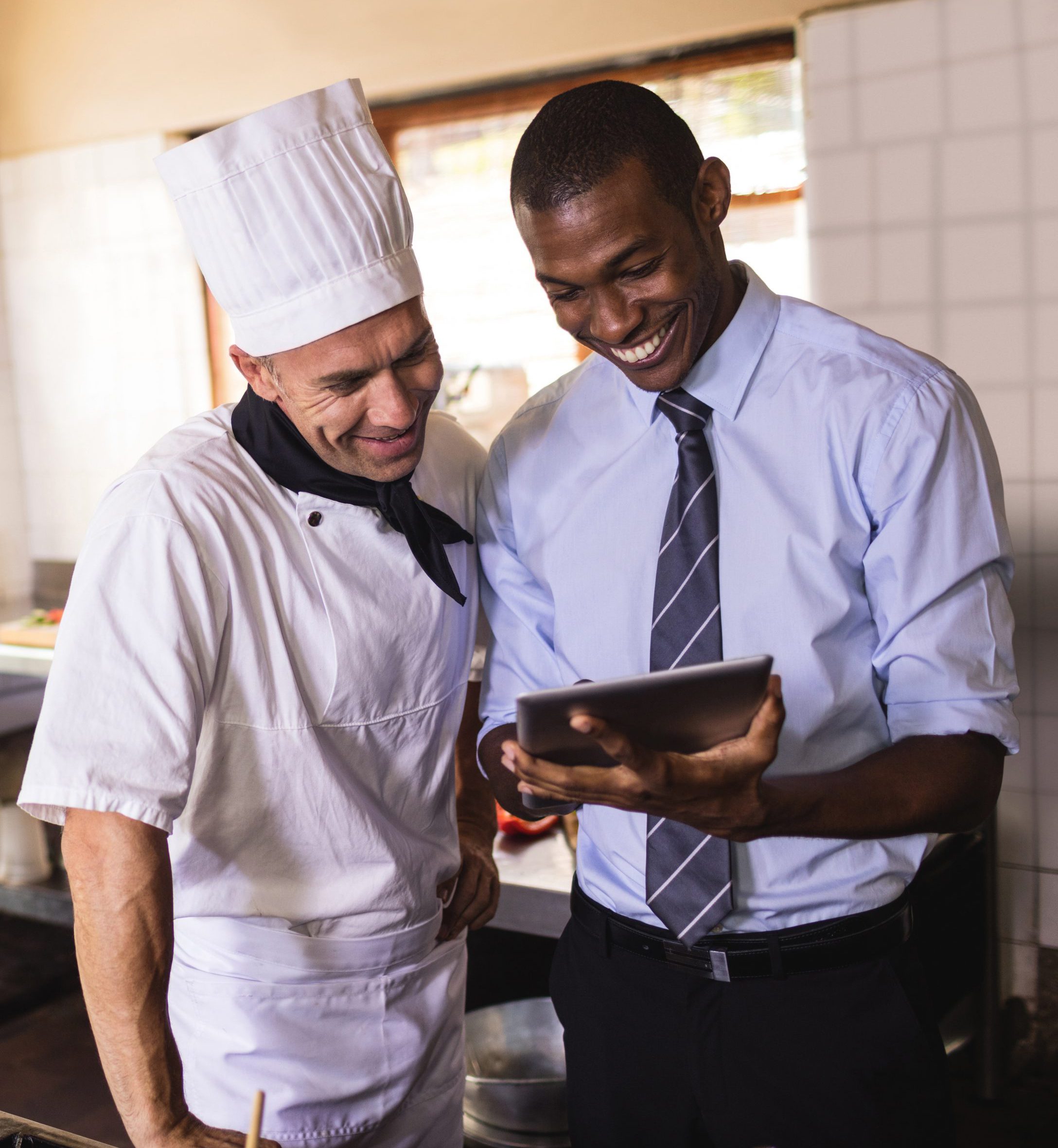 School nutrition manager and cook review production results on a tablet